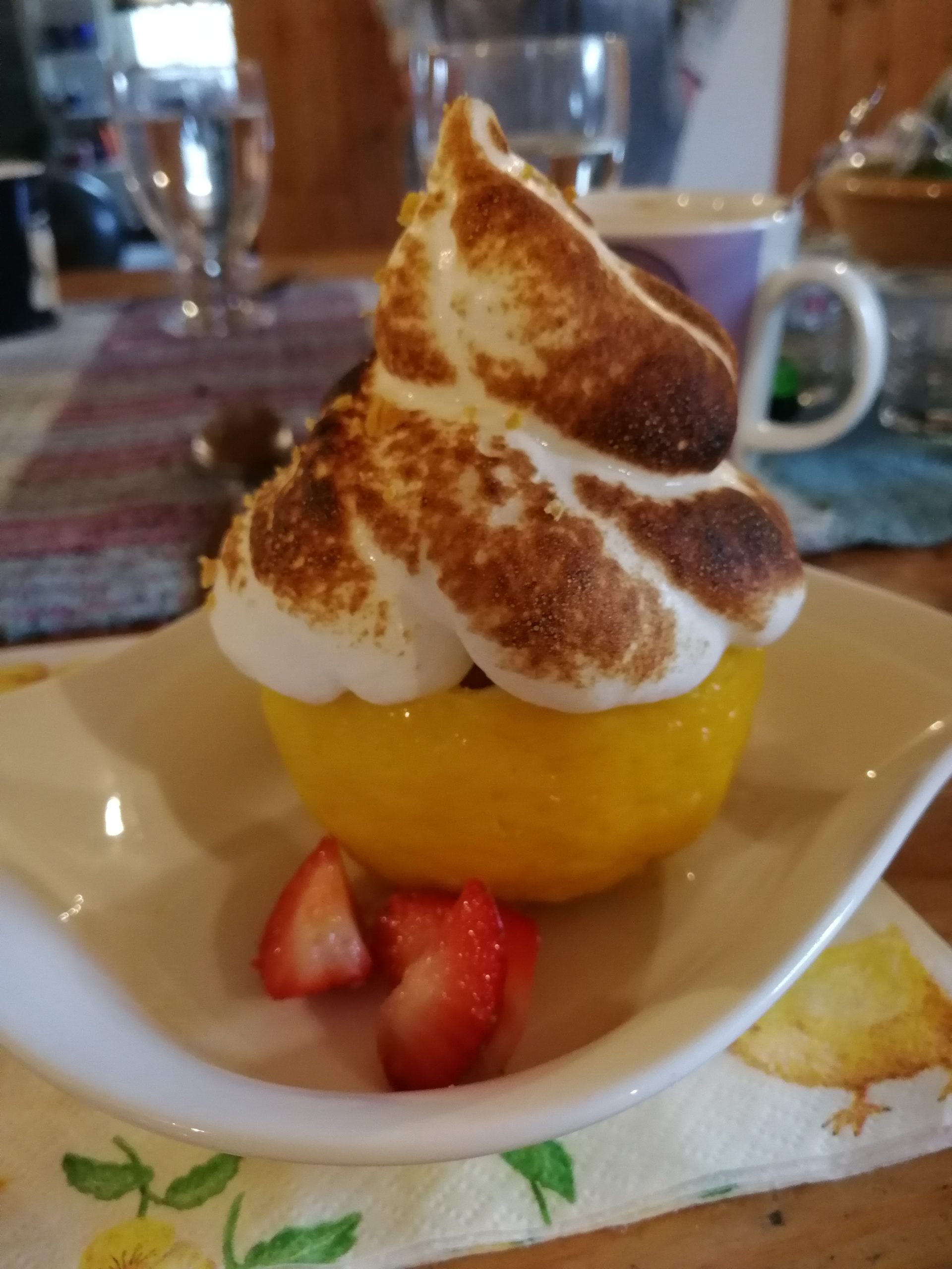 Sitruunanpuolikkaan sisään tehty jälkiruoka, josta näkyvissä on paahdettu marenkipäällys