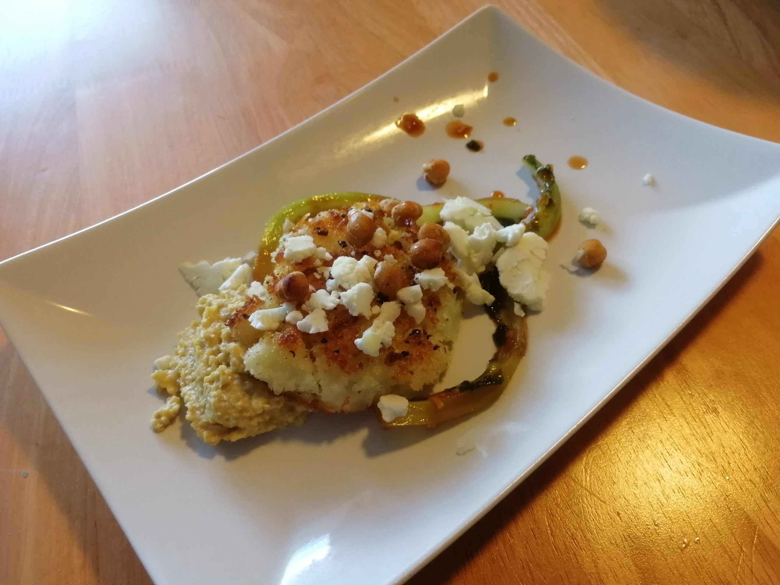 Leivitetty kukkakaalipihvi, kukkakaalikimchi, kukkakaalimuru, hummus ja kikherneitä