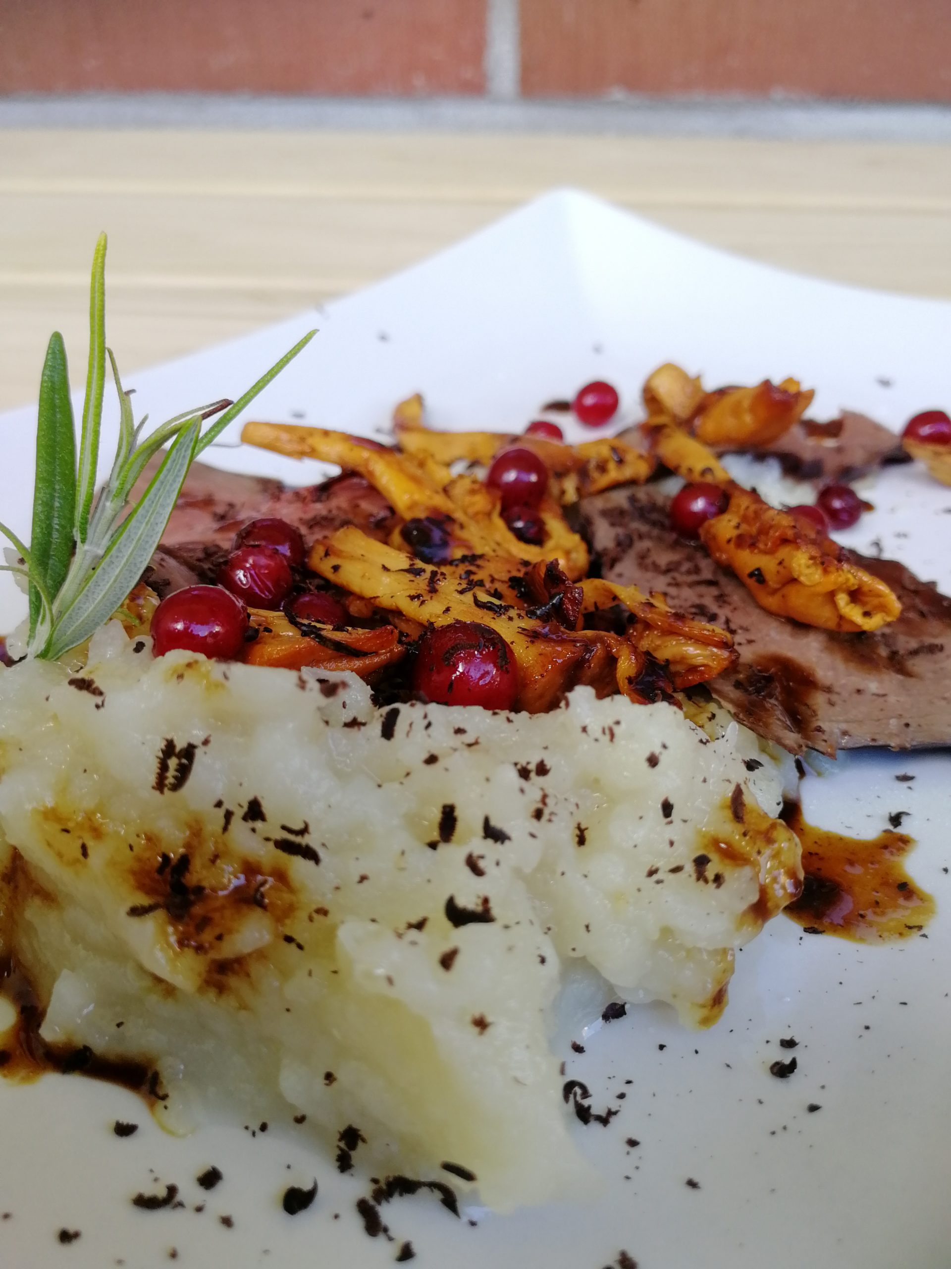 Lautasella maa-artisokkapyree, peuran jääpaistisiivuja, puolukoita, kantarelleja ja raastettua suklaata