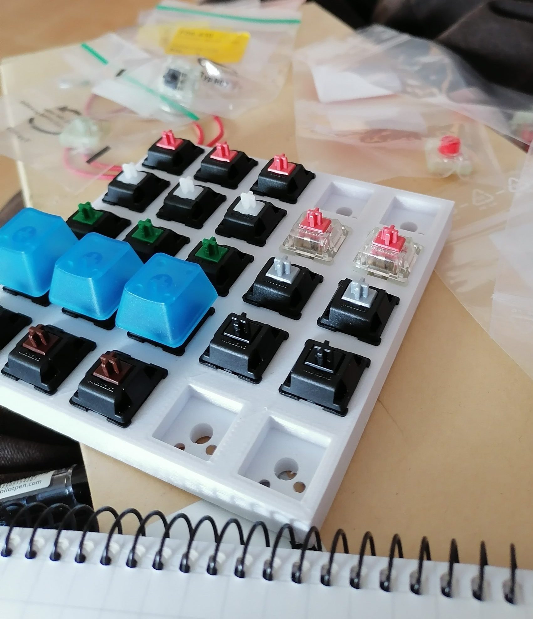 3d-tulostettu 5x5-ruudukko, jonka ruutuihin on asetettu näppäimistöhattuja.